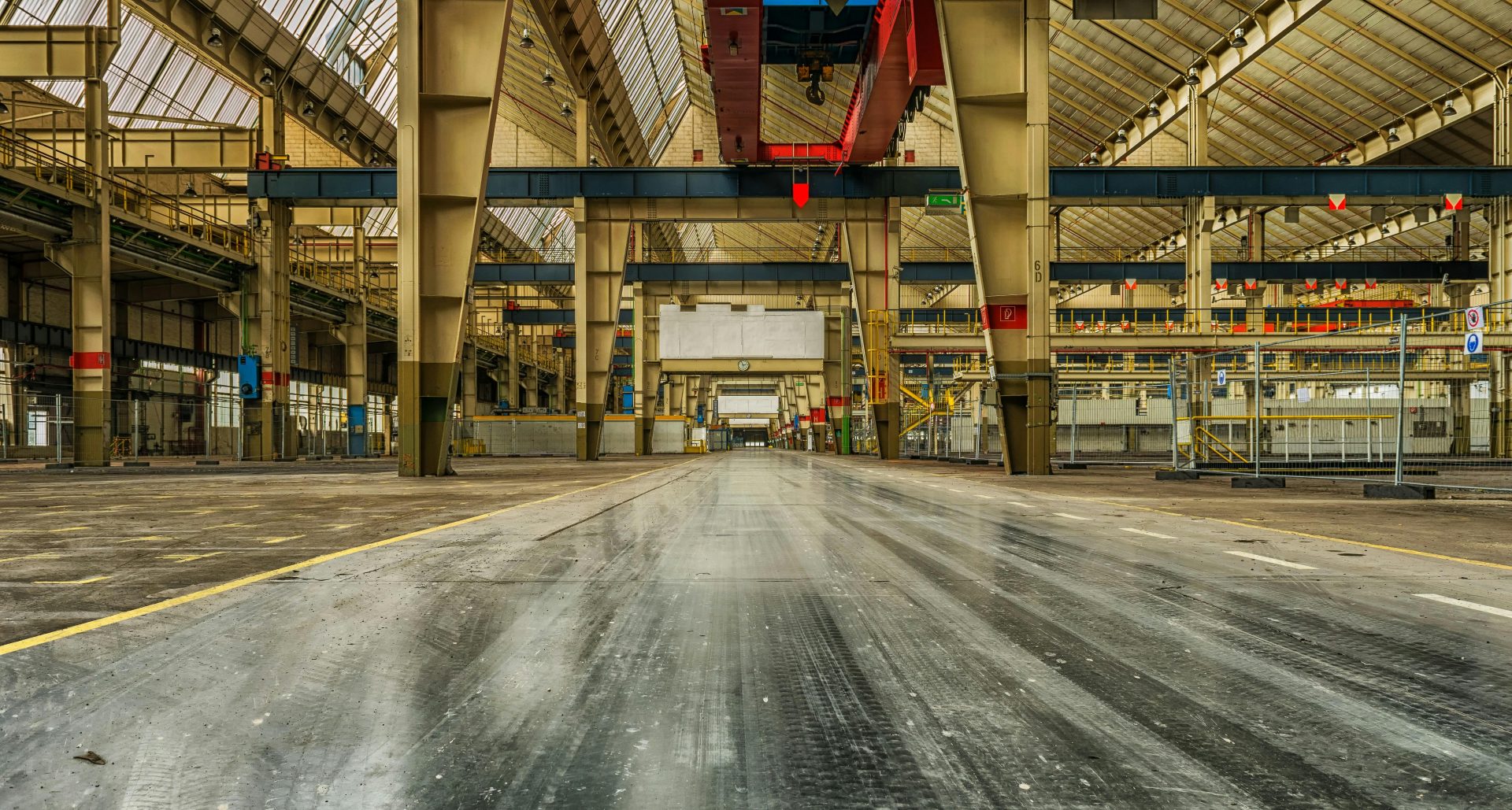 Vista panorámica de una nave industrial vacía con grúas y estructuras metálicas visibles.