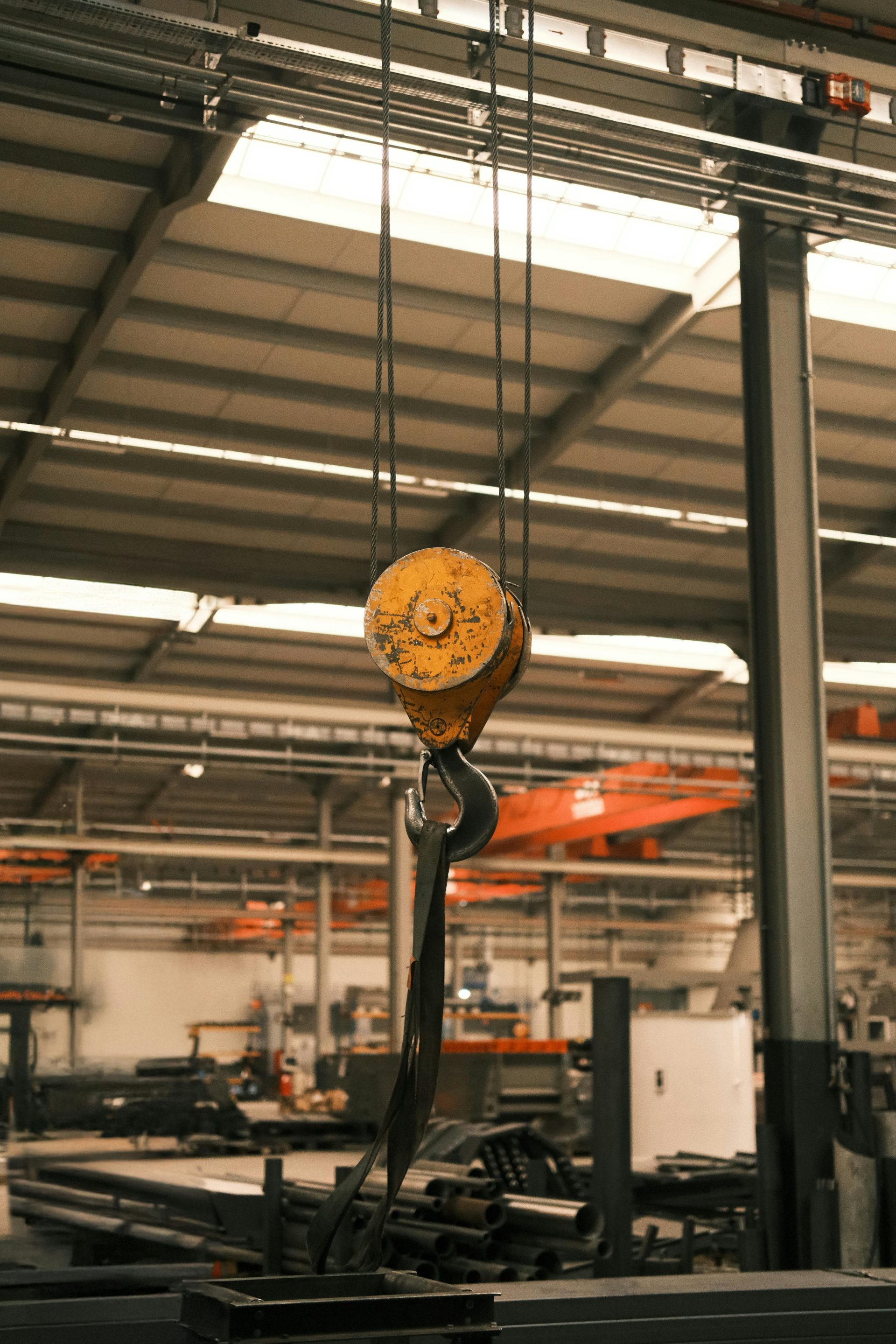 Primer plano del gancho de una grúa industrial en un entorno de fábrica. Ideal para temas relacionados con la tecnología y la fabricación.