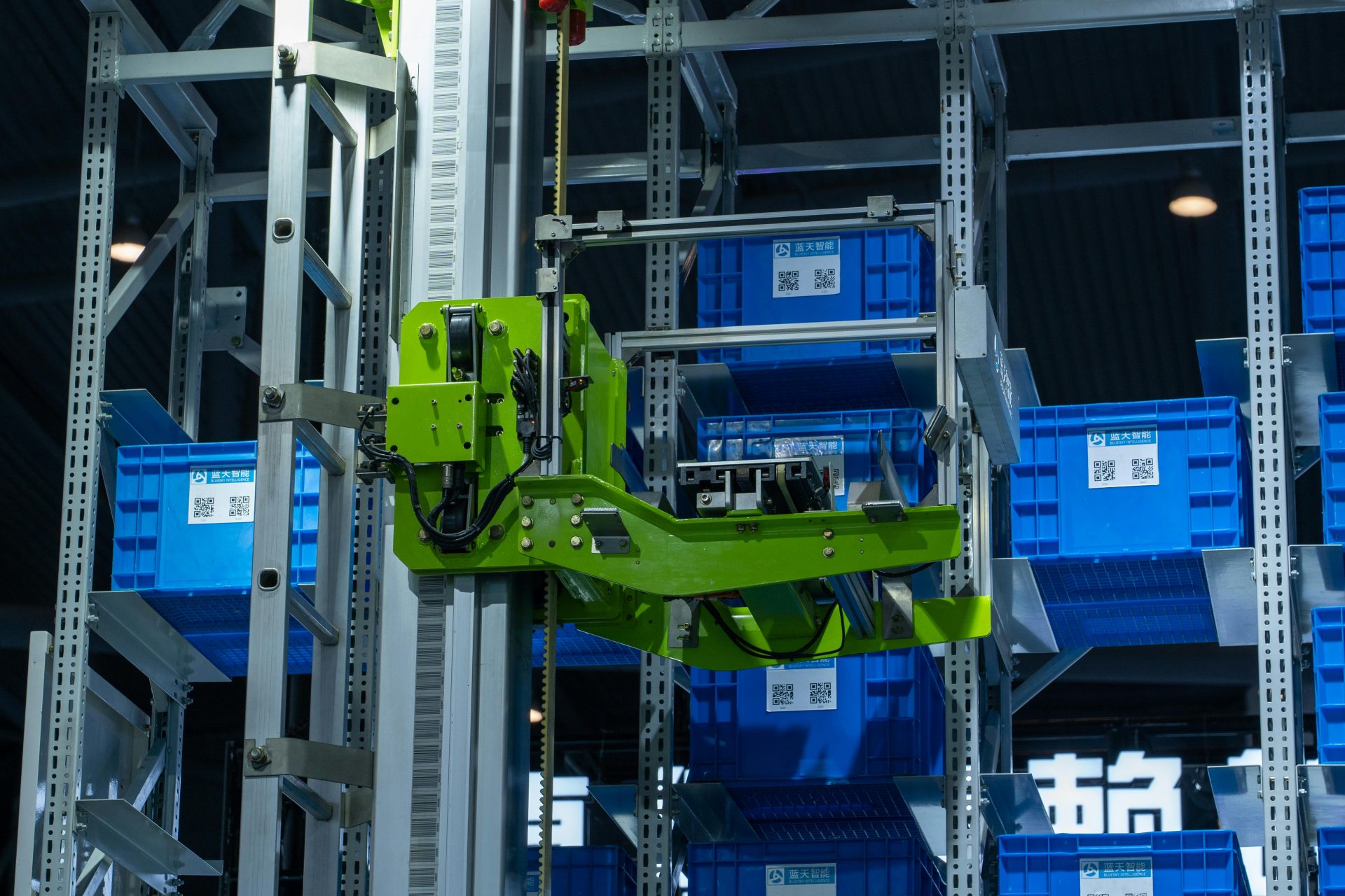 Sistema de almacén automatizado de alta tecnología que cuenta con un brazo robótico verde que manipula cajas de almacenamiento azules.