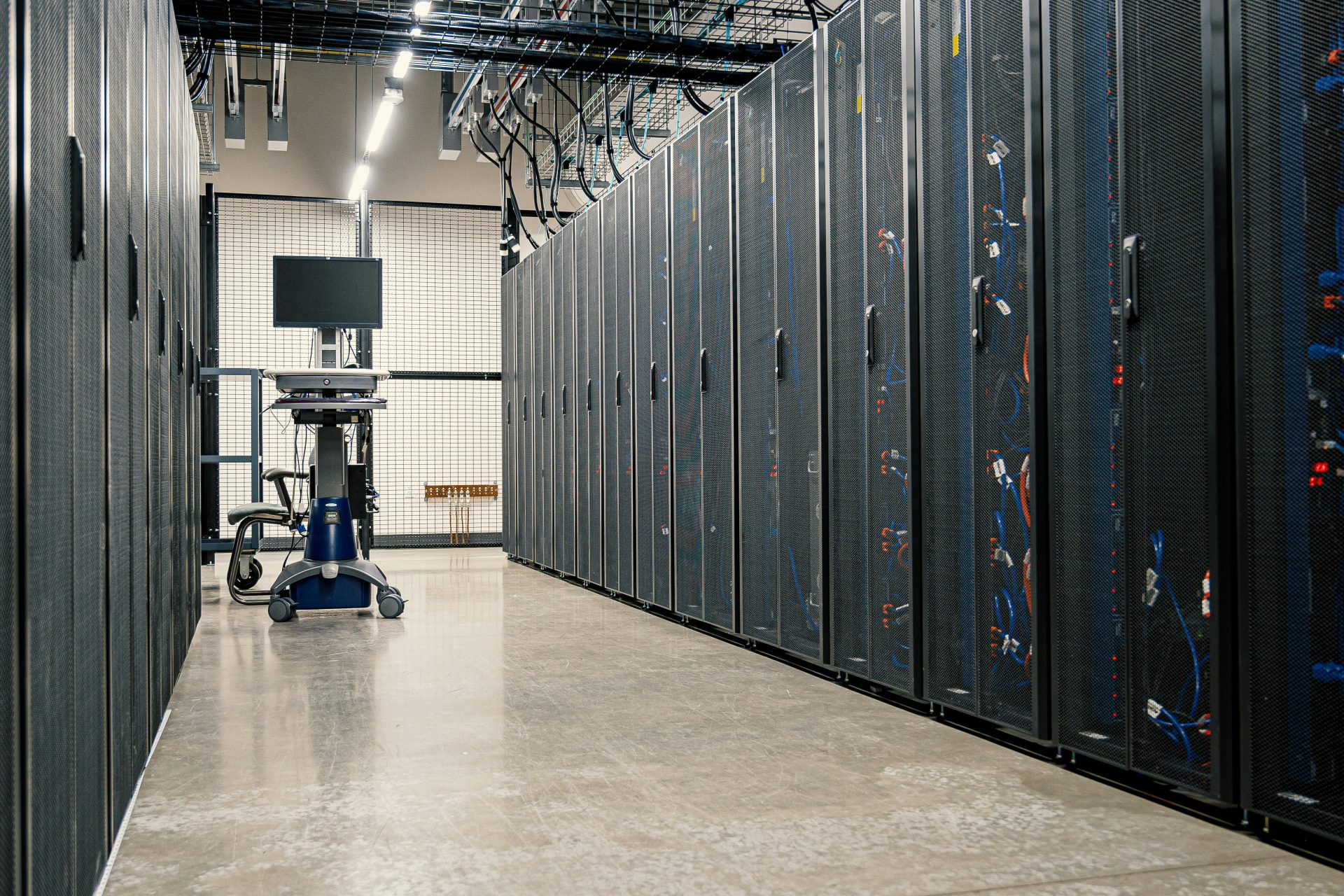 Armarios con estructura de acero que albergan servidores, dispositivos de red y cables en un centro de datos moderno y equipado.